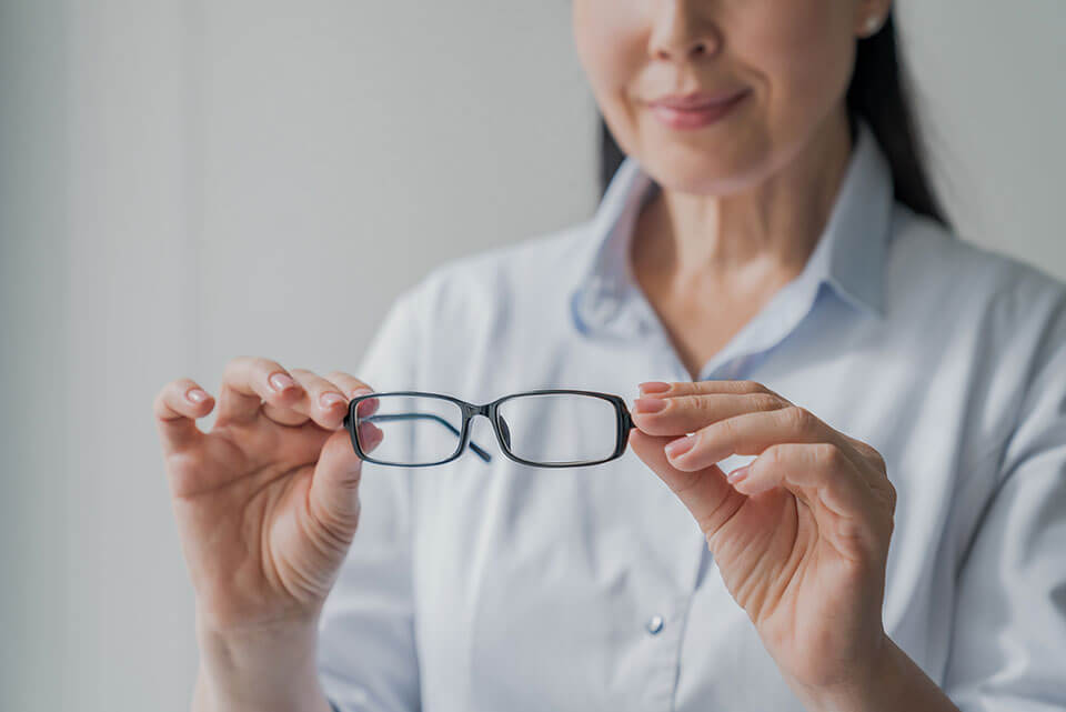a woman checking her glasses and realizing the importance of visiting her eye doctor