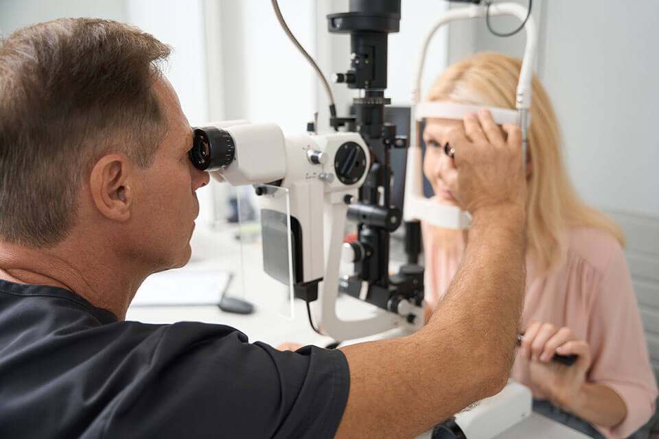 Retina specialist examines patient's eyes with an instrument