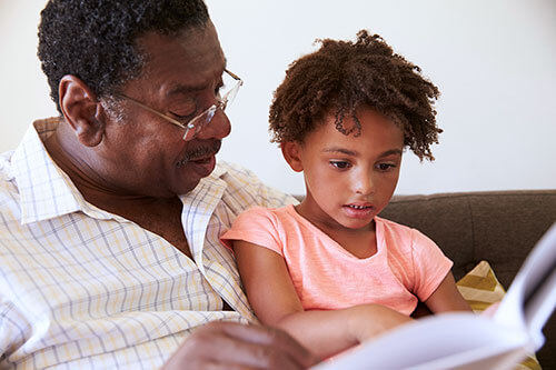 Man reads to his granddaughter with restored vision with the help from retina specialists.