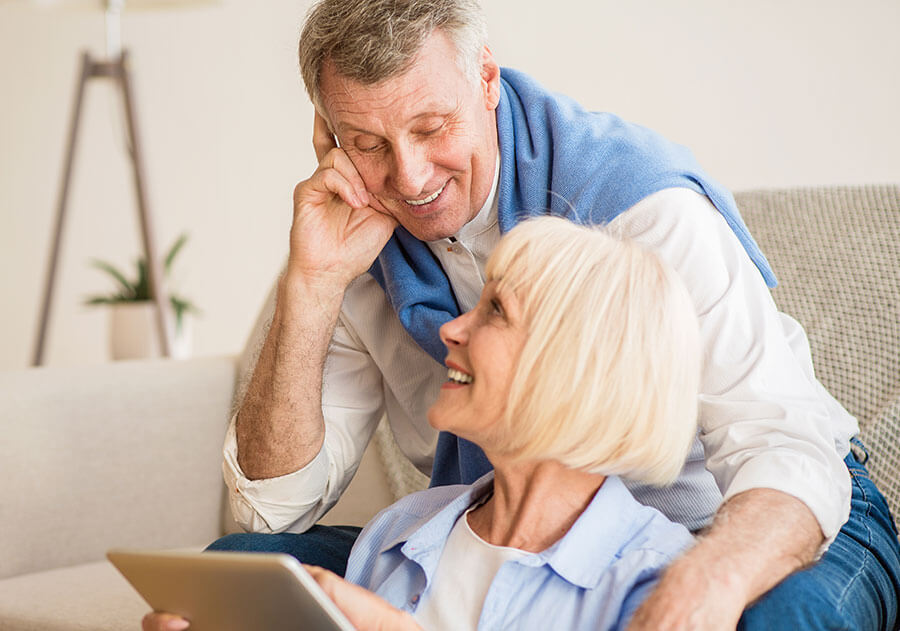 Happy elderly couple reading on tablet after eye clinic treatment