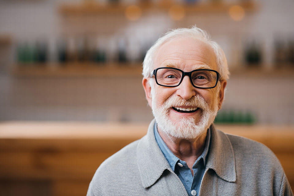 elderly man smiling with glasses at eye doctor
